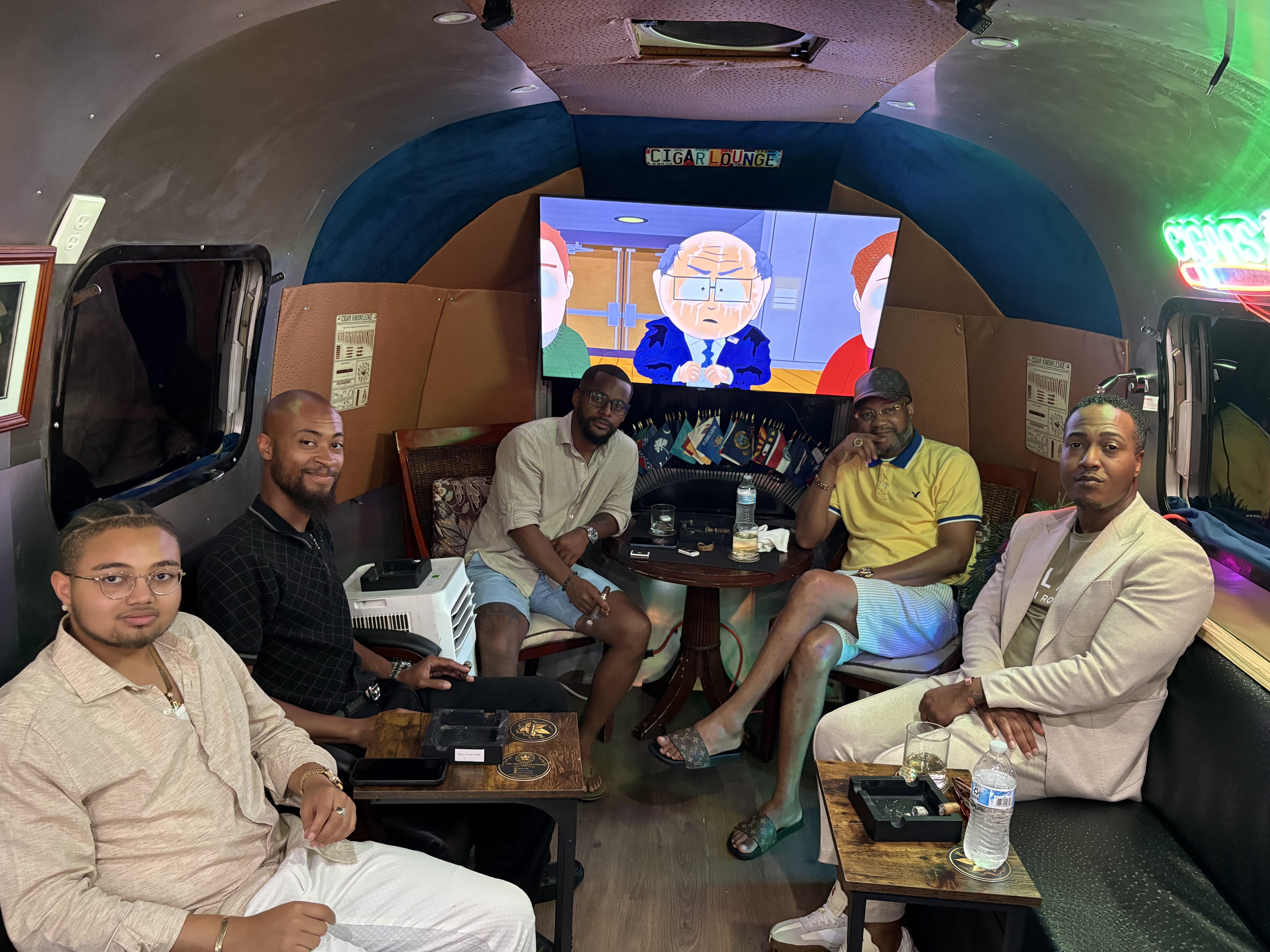 A group of guests posing together under the Cigar Lounge neon sign