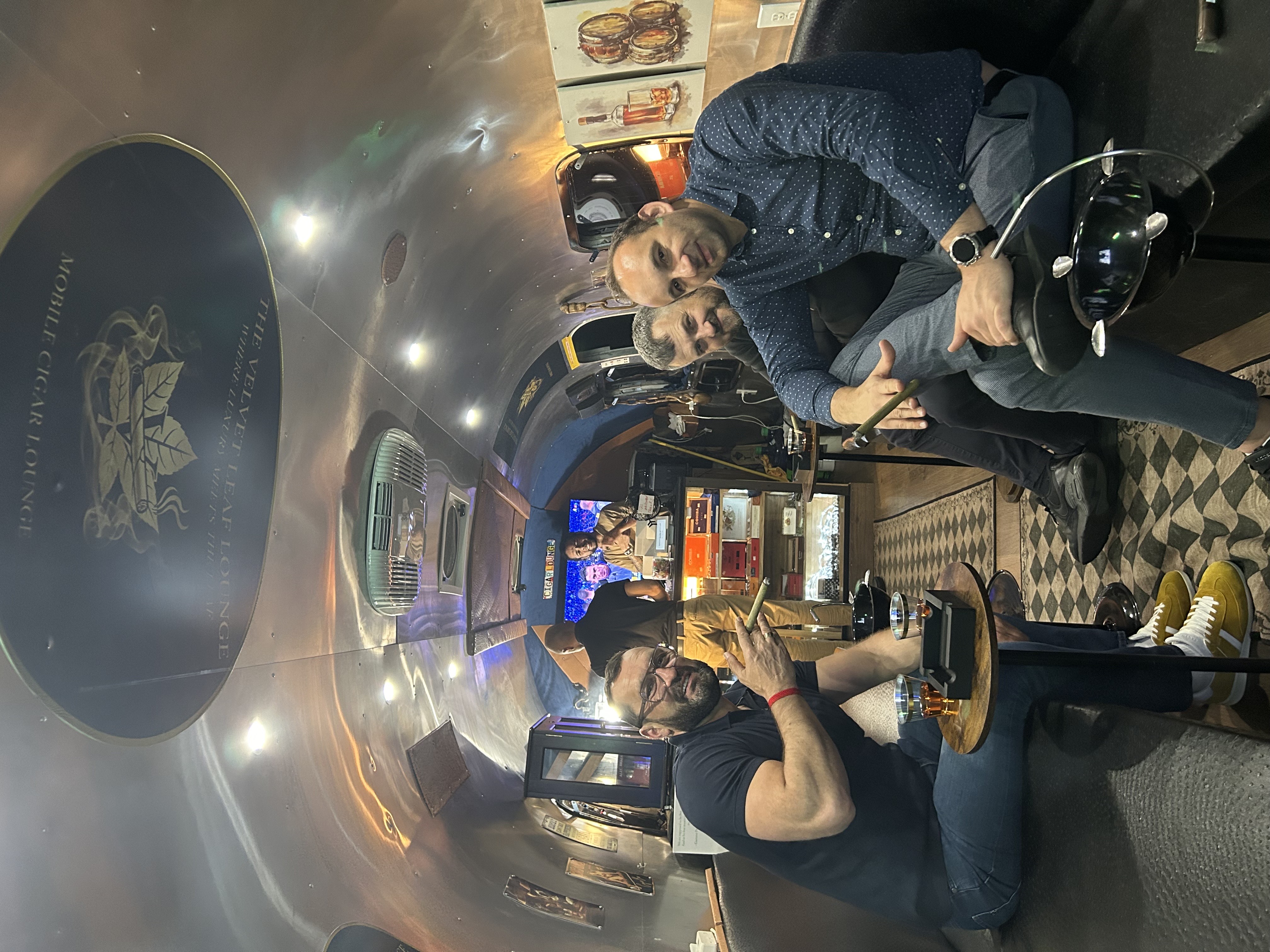 Guests posing with cigars beside The Velvet Leaf Lounge branded table