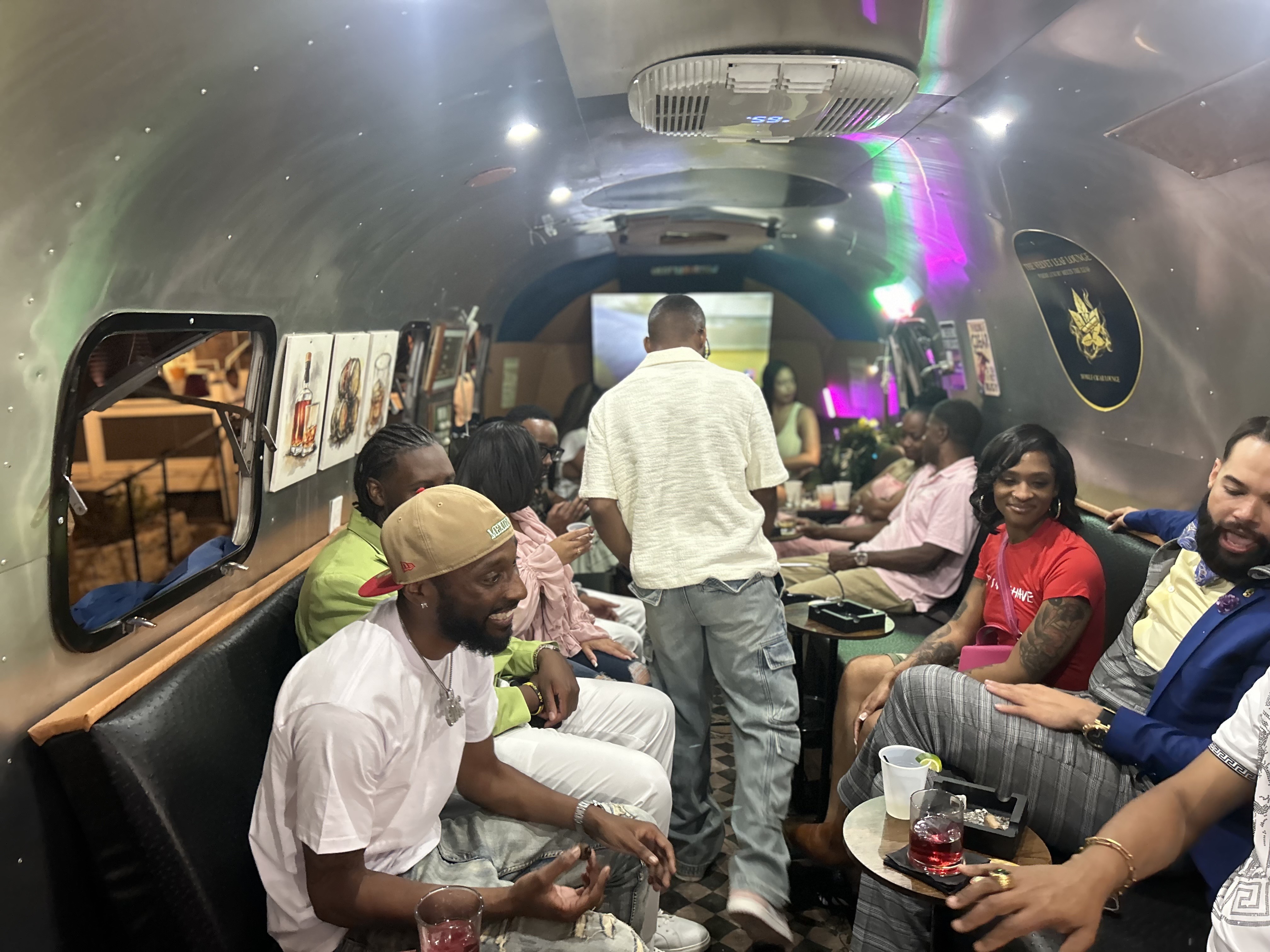 Guests relaxing inside the Airstream lounge under colorful ambient lighting